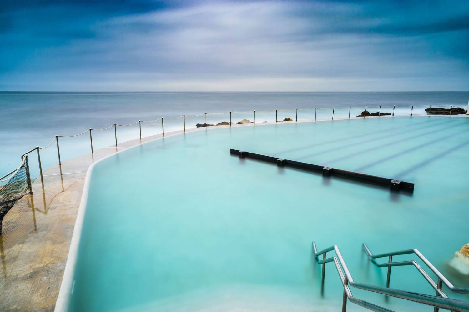 Tranquil scene of Bronte ocean pool with calm waters and blue sky, perfect for leisure and relaxation.