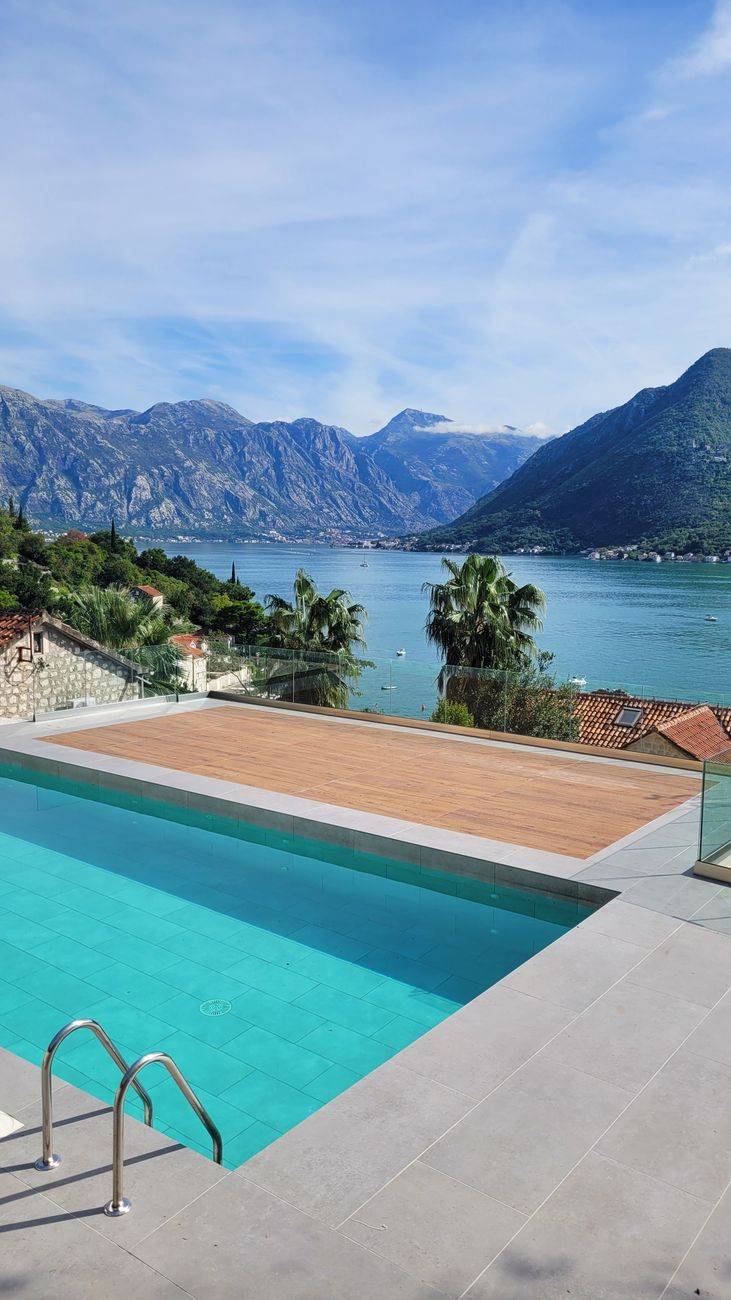 A serene infinity pool with a stunning view of a mountainous bay under a clear sky, ideal for relaxation.