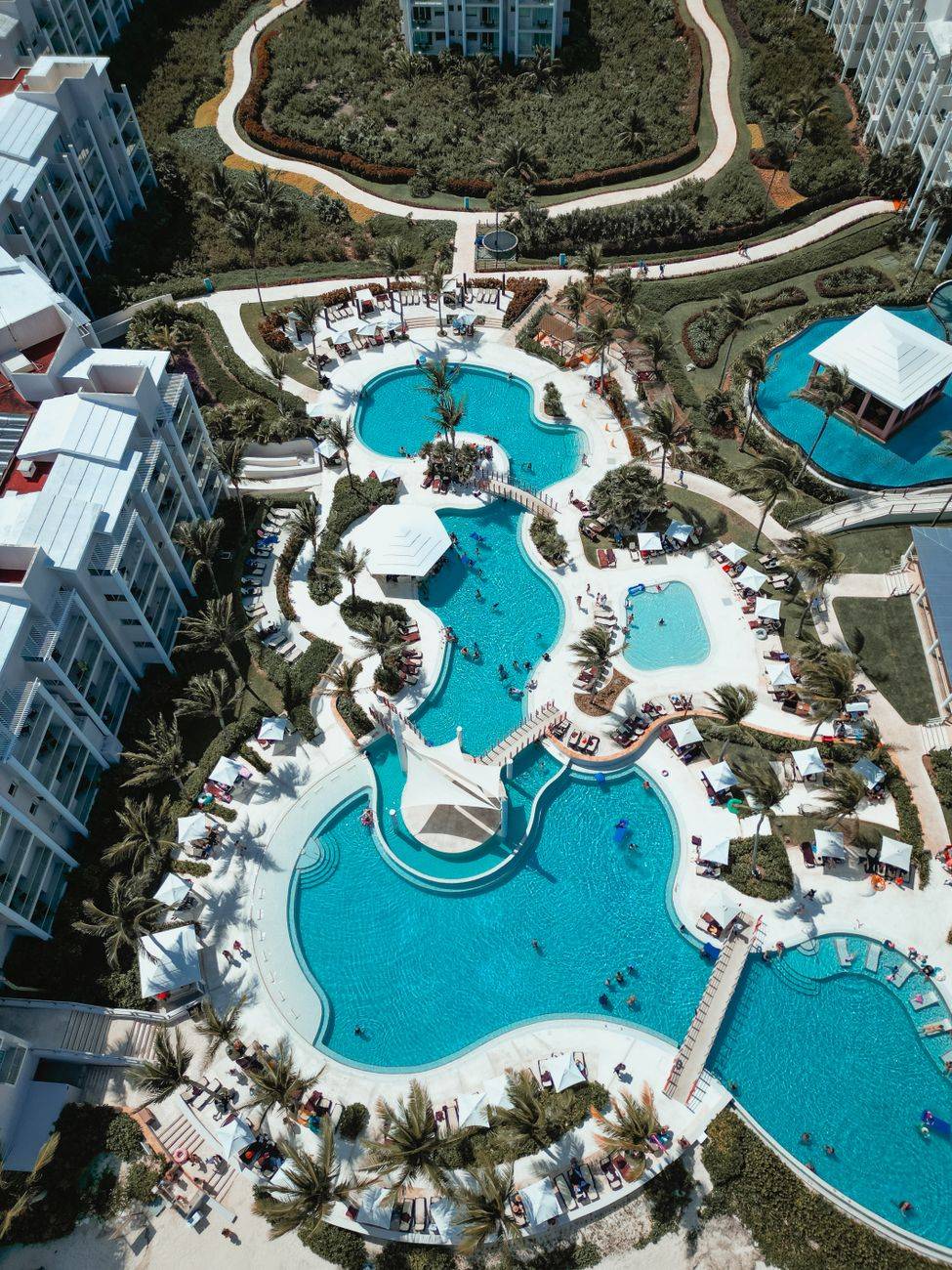 Aerial view of a tropical resort's inviting blue pools and lush surroundings, perfect for relaxation.