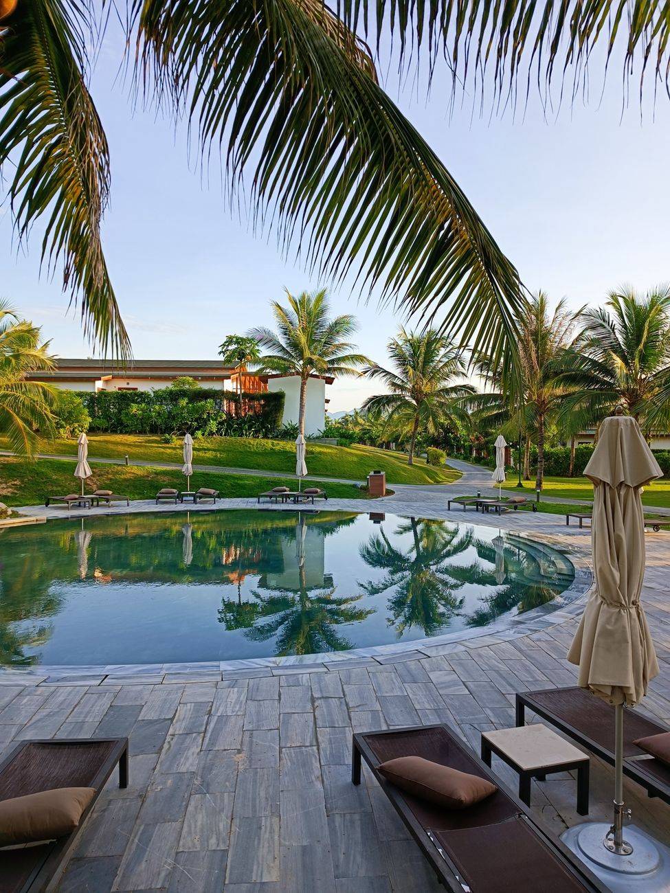 Luxurious tropical resort with palm trees surrounding a sparkling round swimming pool.
