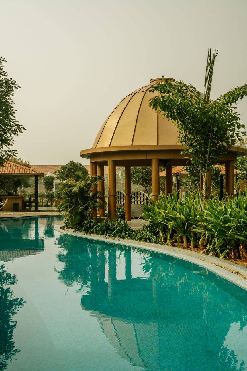 Captivating view of a luxury swimming pool and gazebo surrounded by lush greenery in India.