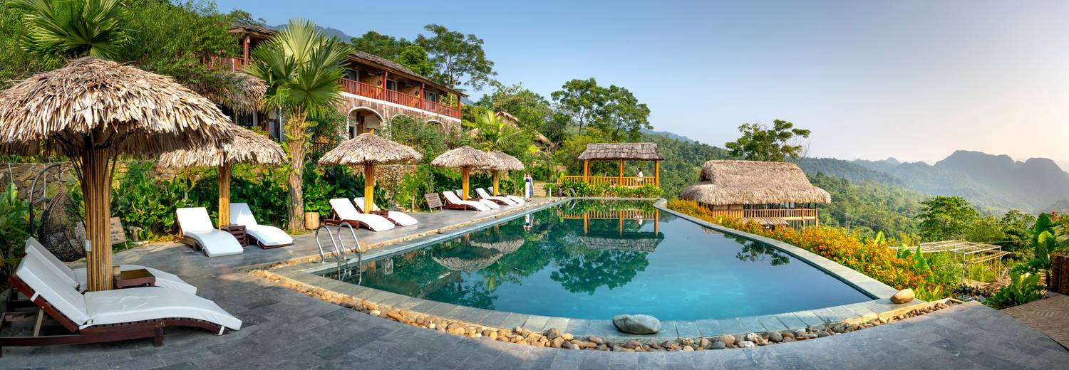 Exotic resort hotel with swimming pool with deckchairs and umbrellas located in calm tropical place