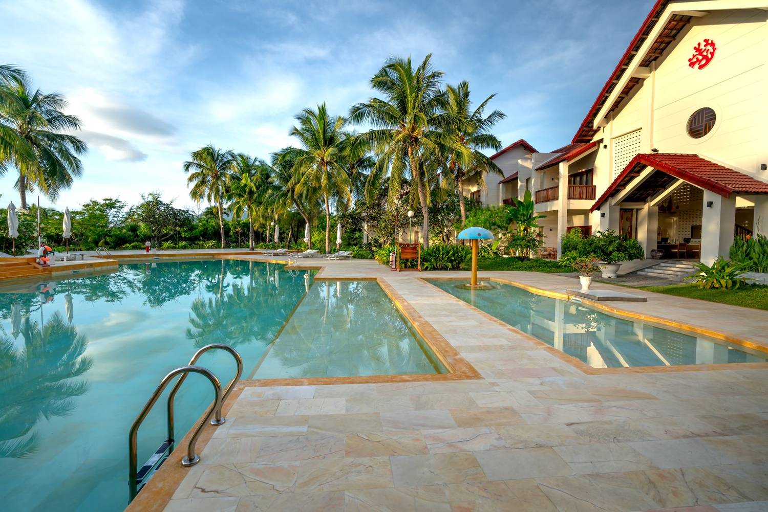 Relax by the luxurious pool with palm trees at a tropical resort.