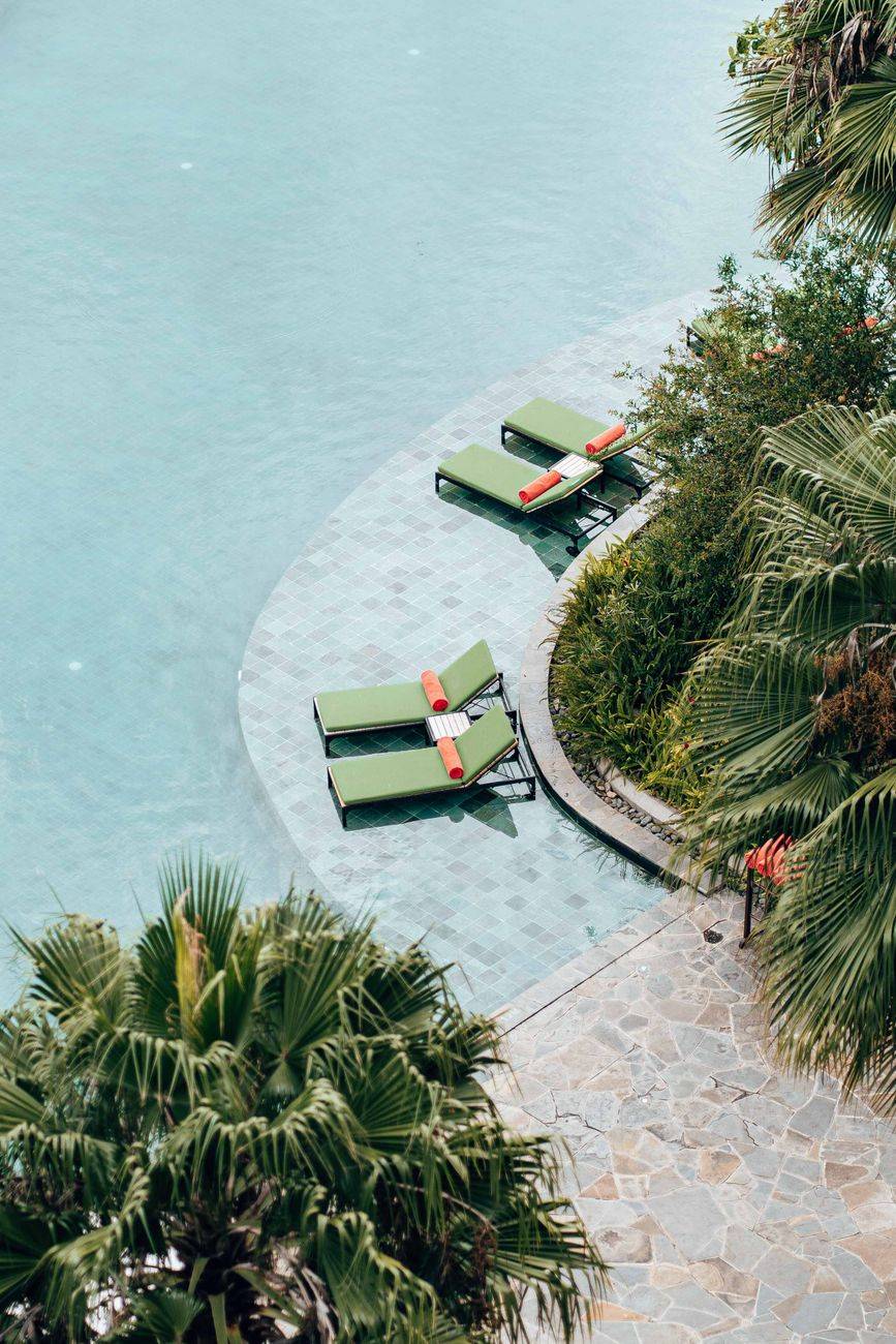 Relaxing poolside scene with lounge chairs and palm trees, capturing a serene vacation vibe.