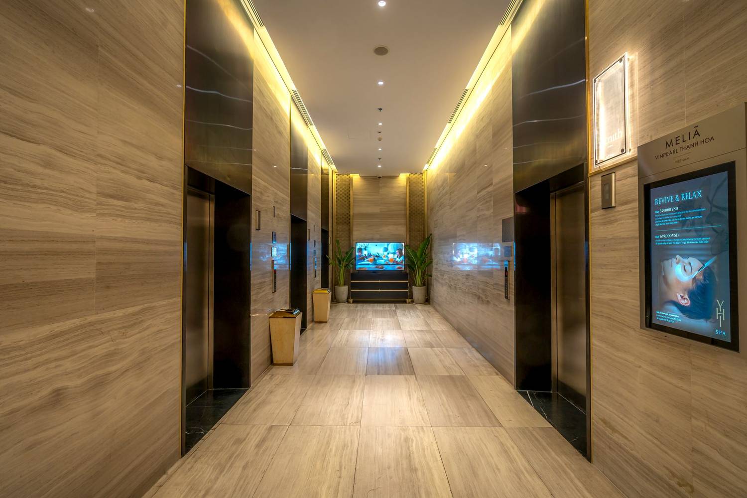 Elegant hotel corridor featuring marble floors and ambient lighting, exuding luxury.