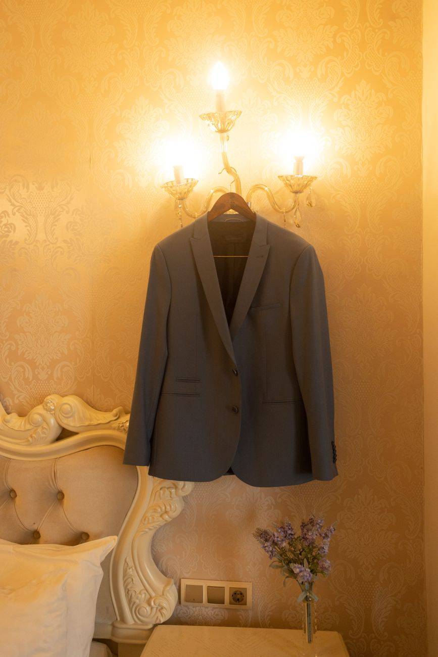 A sophisticated suit hangs on a luxurious lamp in a Milan hotel room, exuding elegance and style.