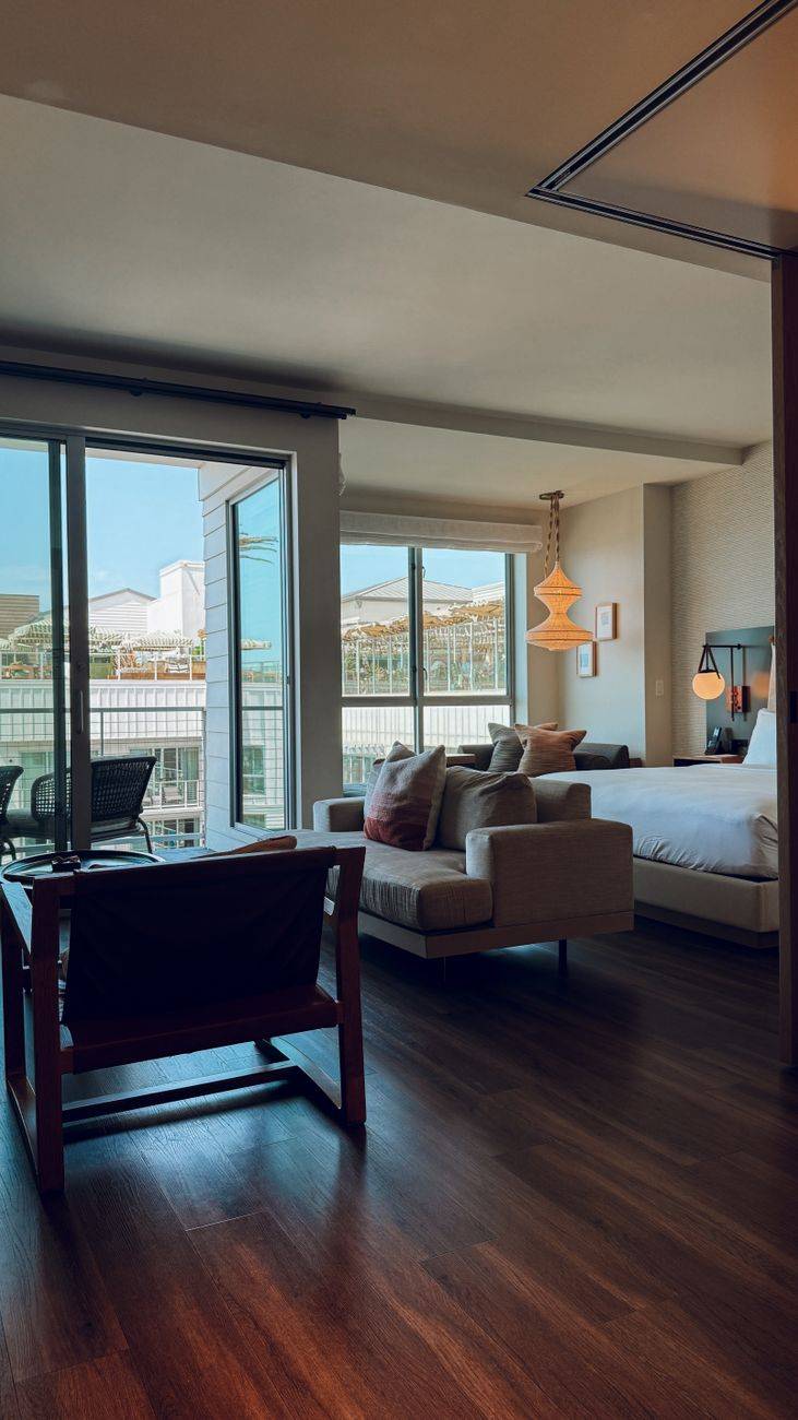 Cozy modern hotel room with large windows overlooking cityscape and stylish decor.
