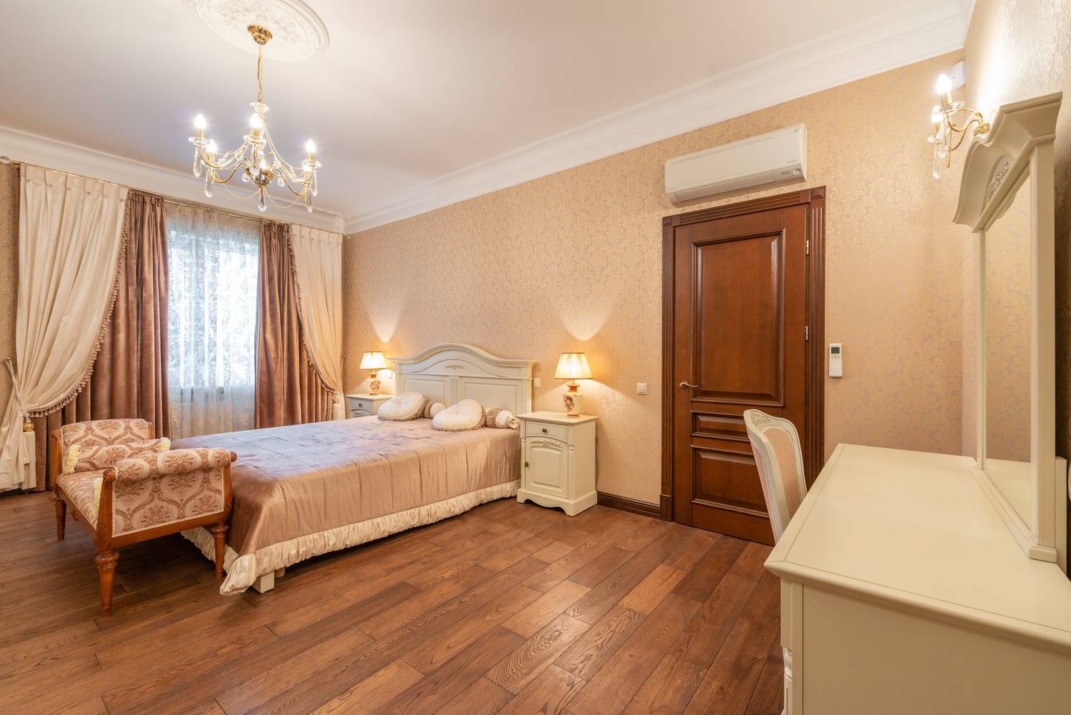 Luxurious hotel room with classic decor featuring a bed, vanity, and wooden flooring.