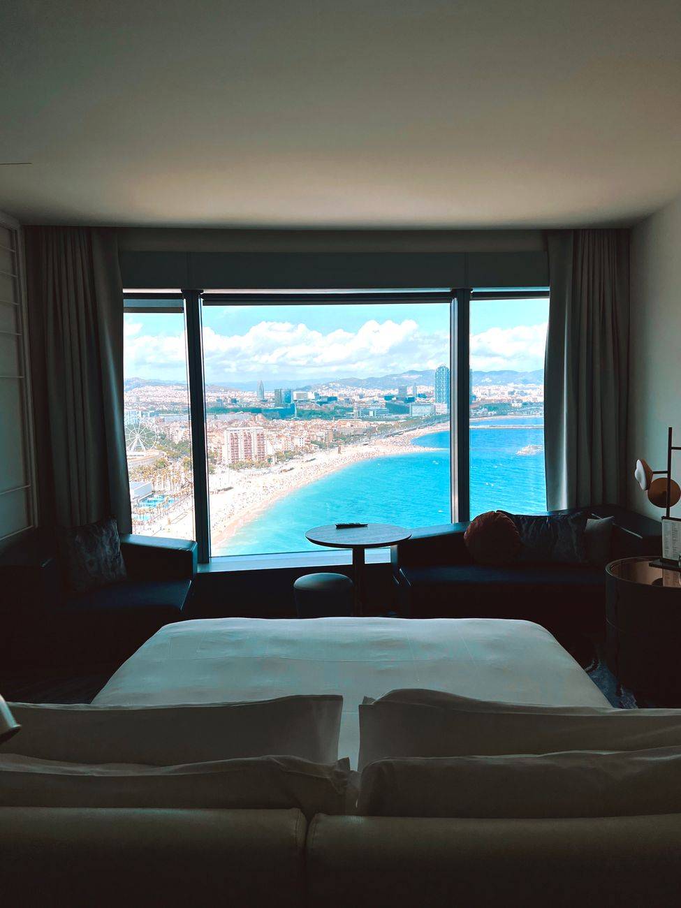 Luxurious hotel room with a stunning beach and city view from a large window.