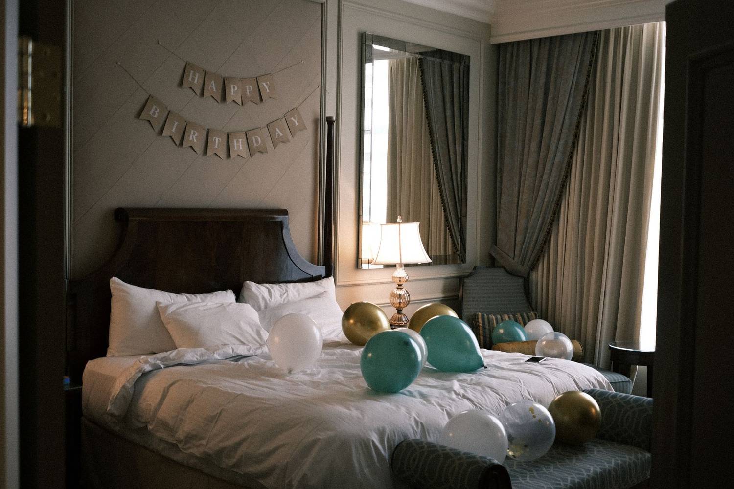 Elegant hotel room decorated with balloons and a 'Happy Birthday' banner, creating a festive atmosphere.