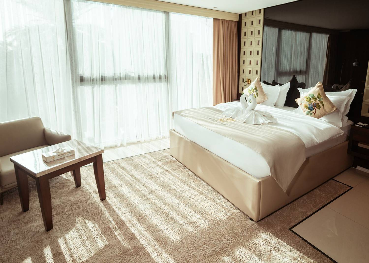 Spacious hotel room with large bed, elegant decor, and natural light in Baghdad, Iraq.