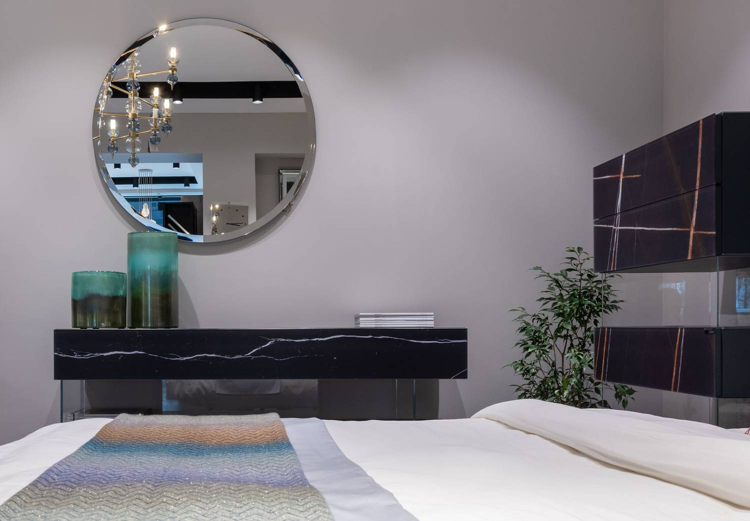 Comfortable large bed with white blanket in modern bedroom with round mirror on wall