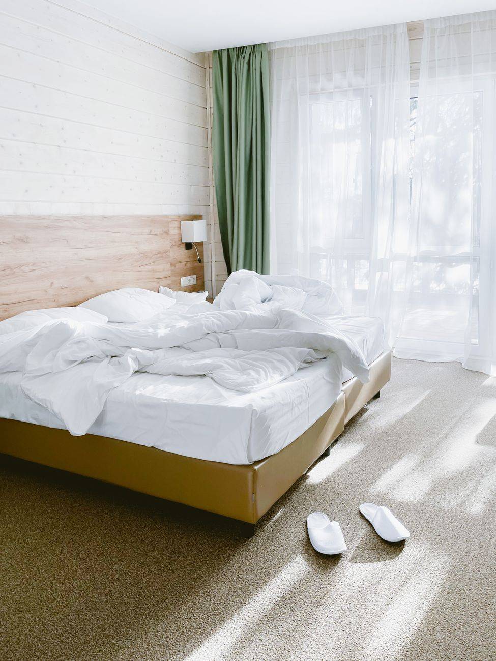 Bright bedroom with an unmade bed, soft natural light filtering through curtains, and cozy interior decor.