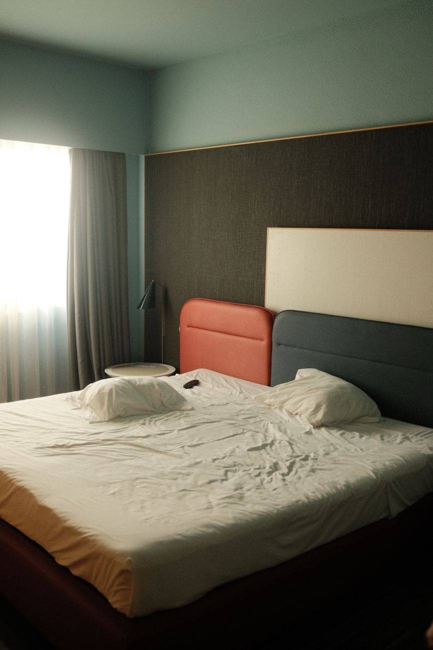 A well-designed modern bedroom featuring a double bed with natural light filtering through curtains.