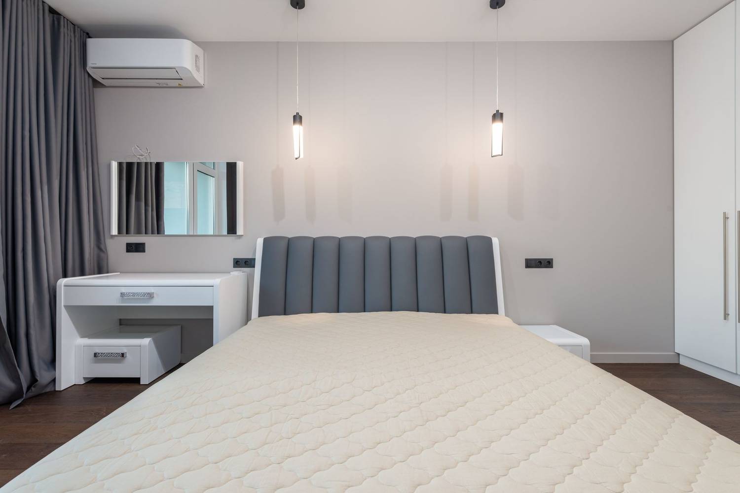 Sleek minimalist bedroom design featuring a plush bed, pendant lighting, and modern furnishings.