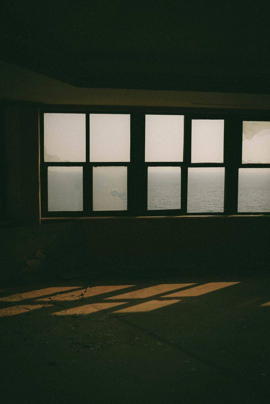 A room overlooking the ocean in Kaş, Antalya, Turkey, filled with dramatic shadows and sunlight.