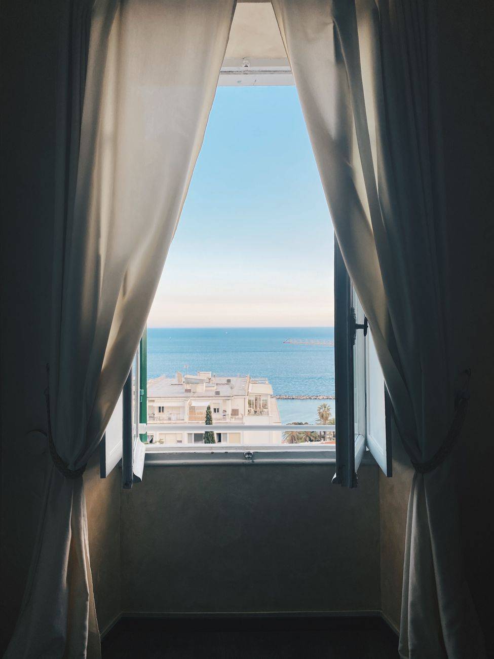 Luxurious window view of the Ligurian Sea in Sanremo, Liguria, Italy with elegant white curtains.