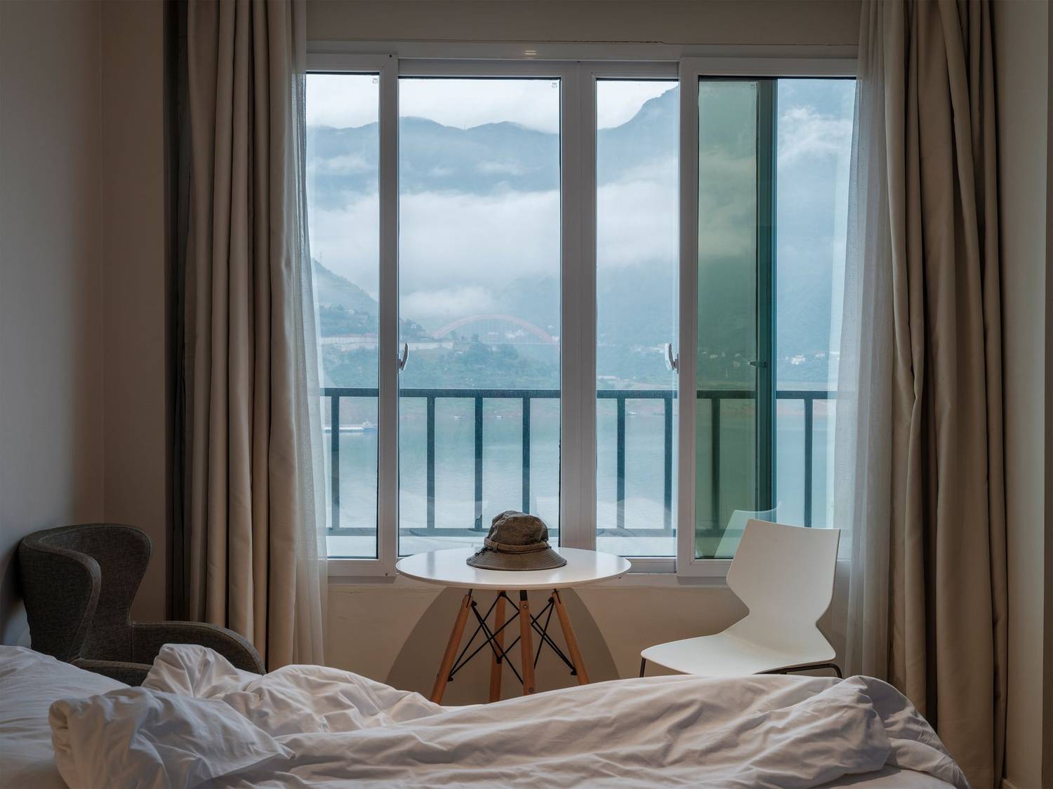 Cozy hotel room with mountain view through large window, perfect for relaxation.