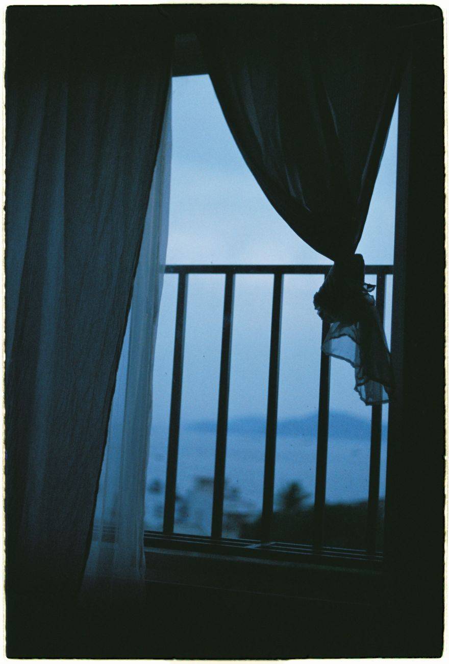A tranquil view of the sea through a window at dawn with flowing curtains.