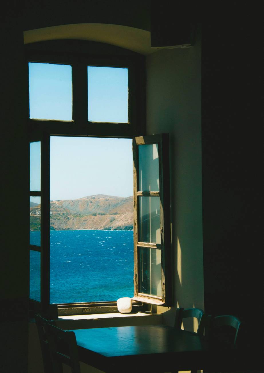 A calming view of the sea and hills through an open window, creating a peaceful indoor setting.