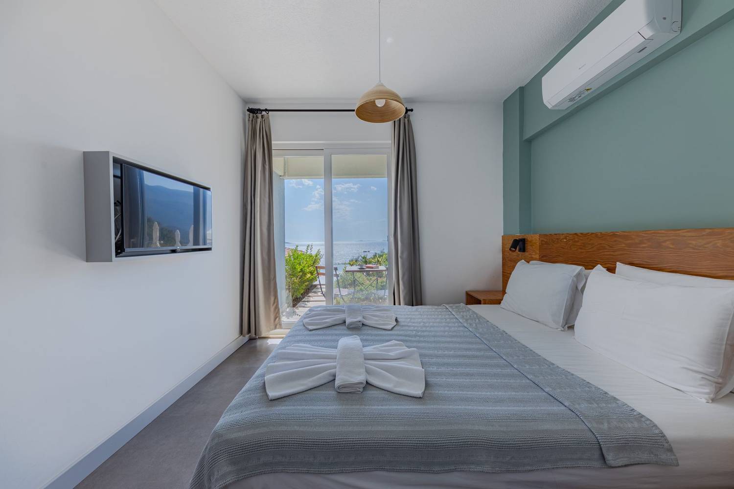 Inviting hotel room with sea view, featuring a neatly arranged bed and modern decor.