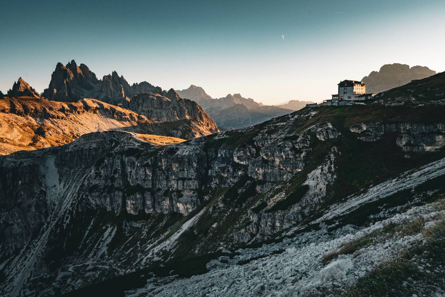 Captivating view of the Dolomites at sunrise, highlighting rugged peaks and a scenic mountain hut.