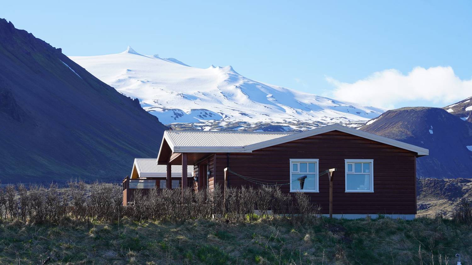 Cozy wooden cabin set against the dramatic Icelandic mountains and glaciers.