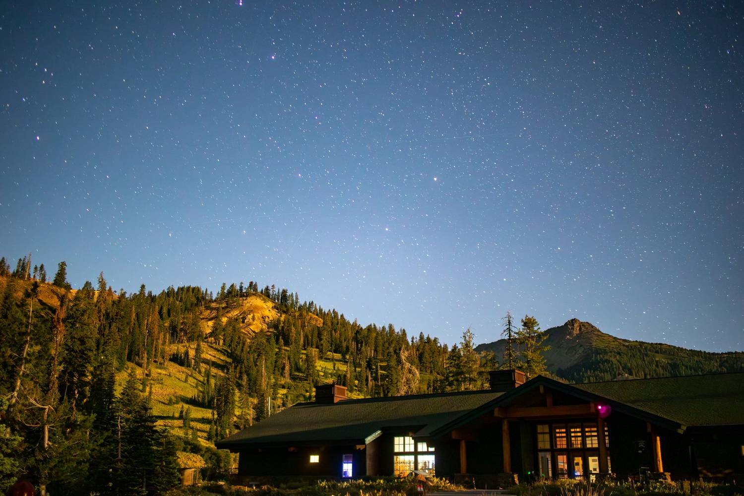A stunning night sky filled with stars above a lodge nestled in the California mountains.