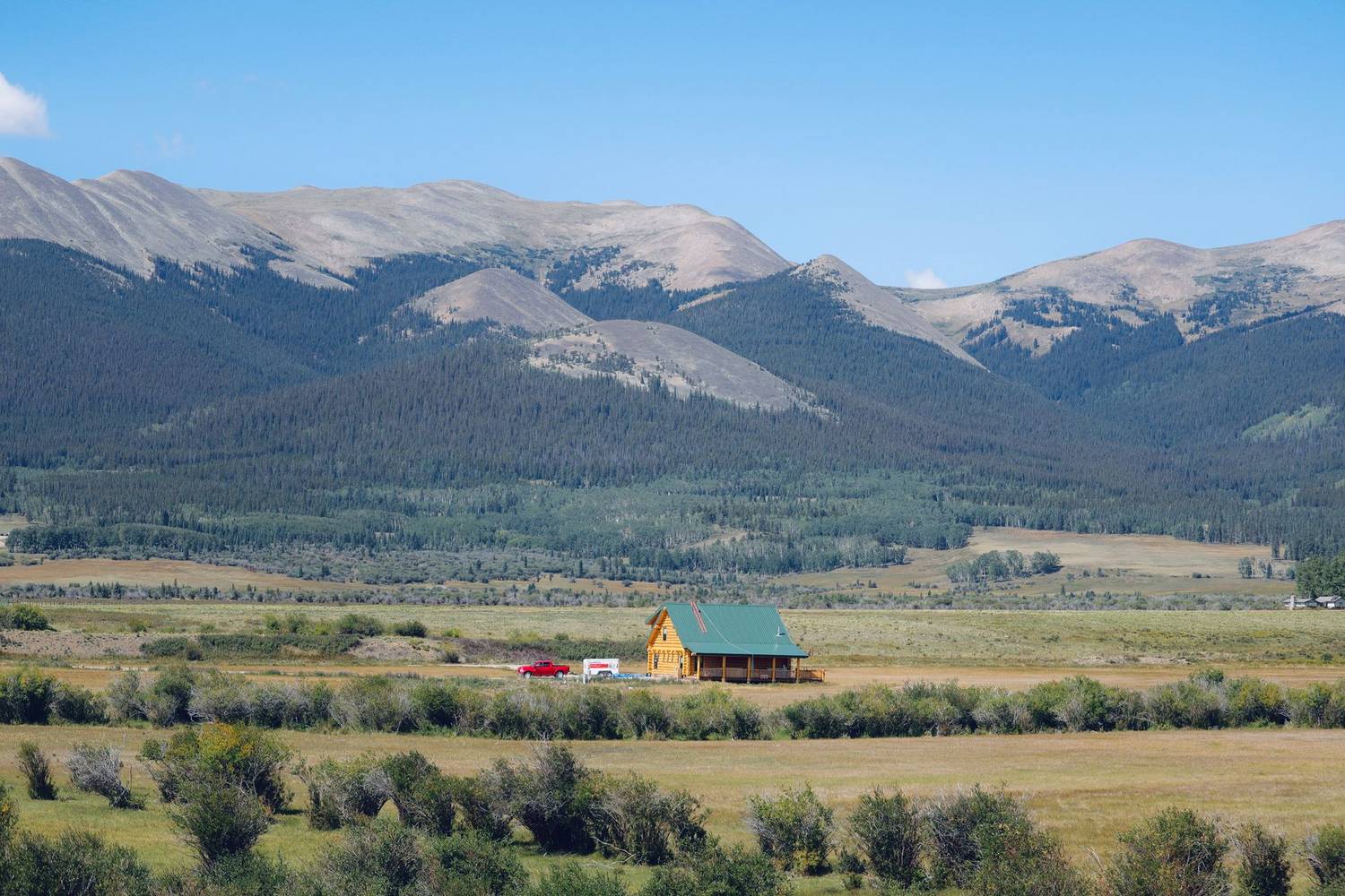 A solitary cabin with mountains in the background, a serene natural setting.