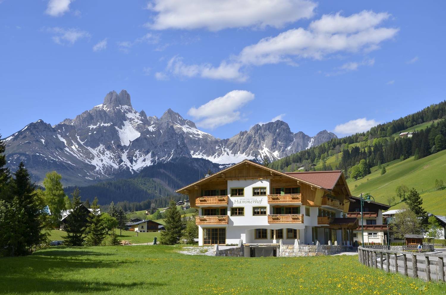 Picturesque lodge nestled in Filzmoos with the stunning Alps in the background under a clear blue sky.