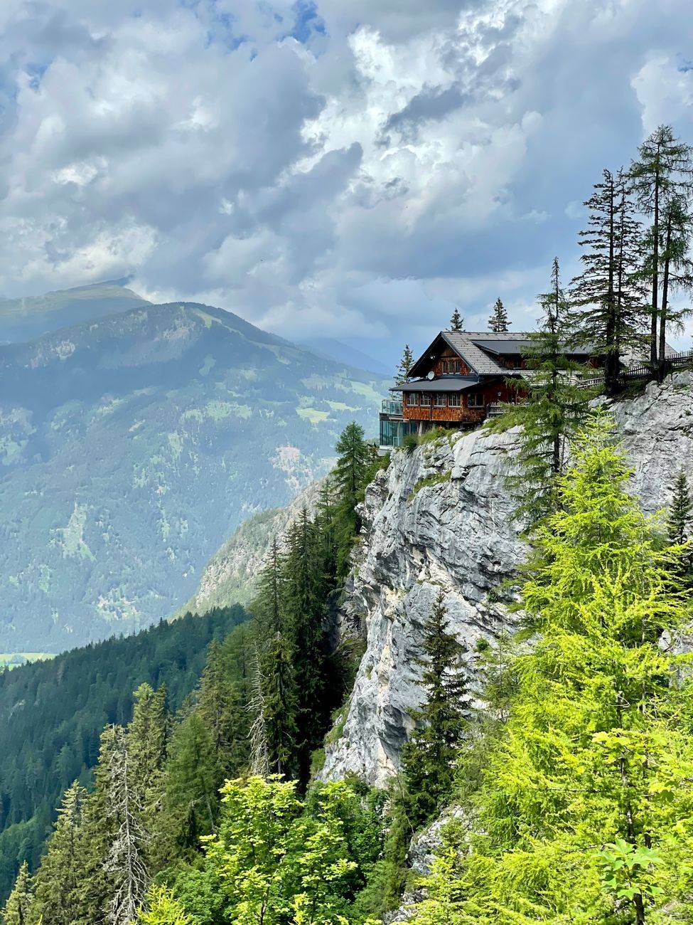 A picturesque lodge perched on a cliffside in Tirol, Austria, surrounded by lush green forests.