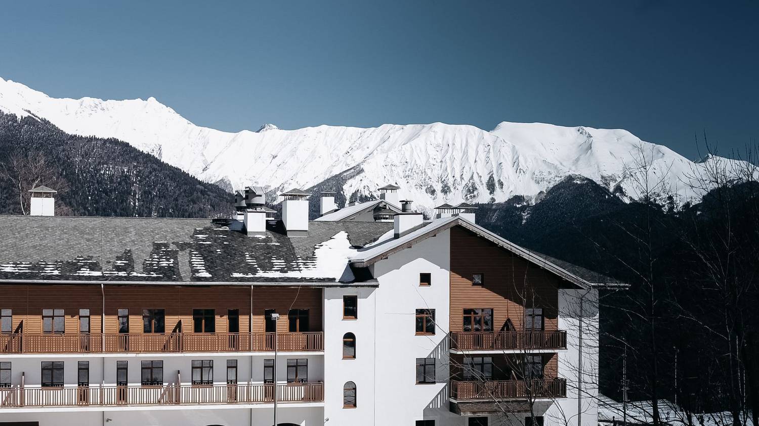 A picturesque wooden lodge nestled in snow-covered mountains near Adler, Russia.