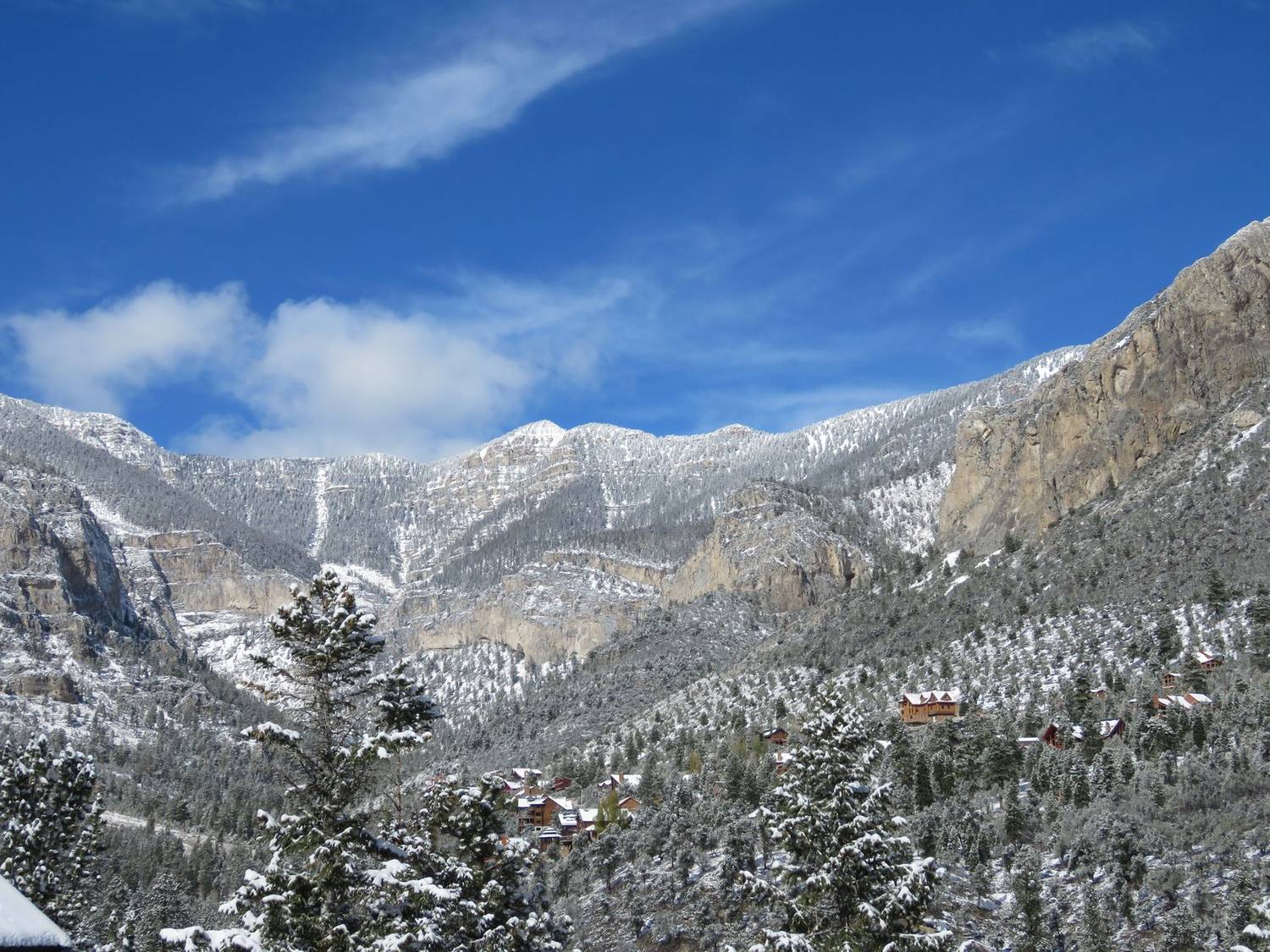 Beautiful winter landscape with snow-covered mountains and evergreen trees under a clear blue sky.