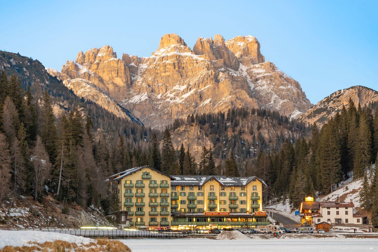 A picturesque hotel nestled among the majestic Dolomite Mountains, captured during a serene winter sunset.